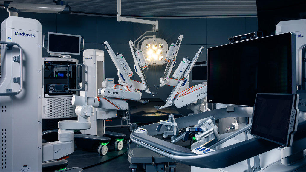Medtronic Hugo RAS system: four modular robotic arms around an operating table, with the surgeon console in the foreground
