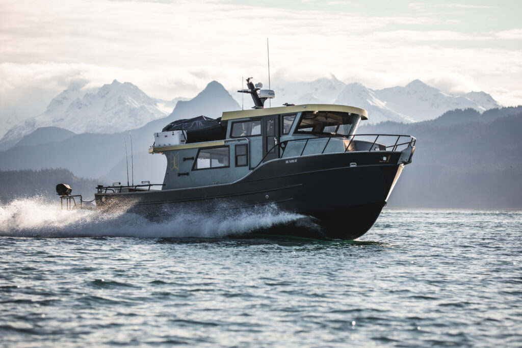 Bay Weld aluminum boat running at speed in Kachemak Bay, snow-capped mountains behind