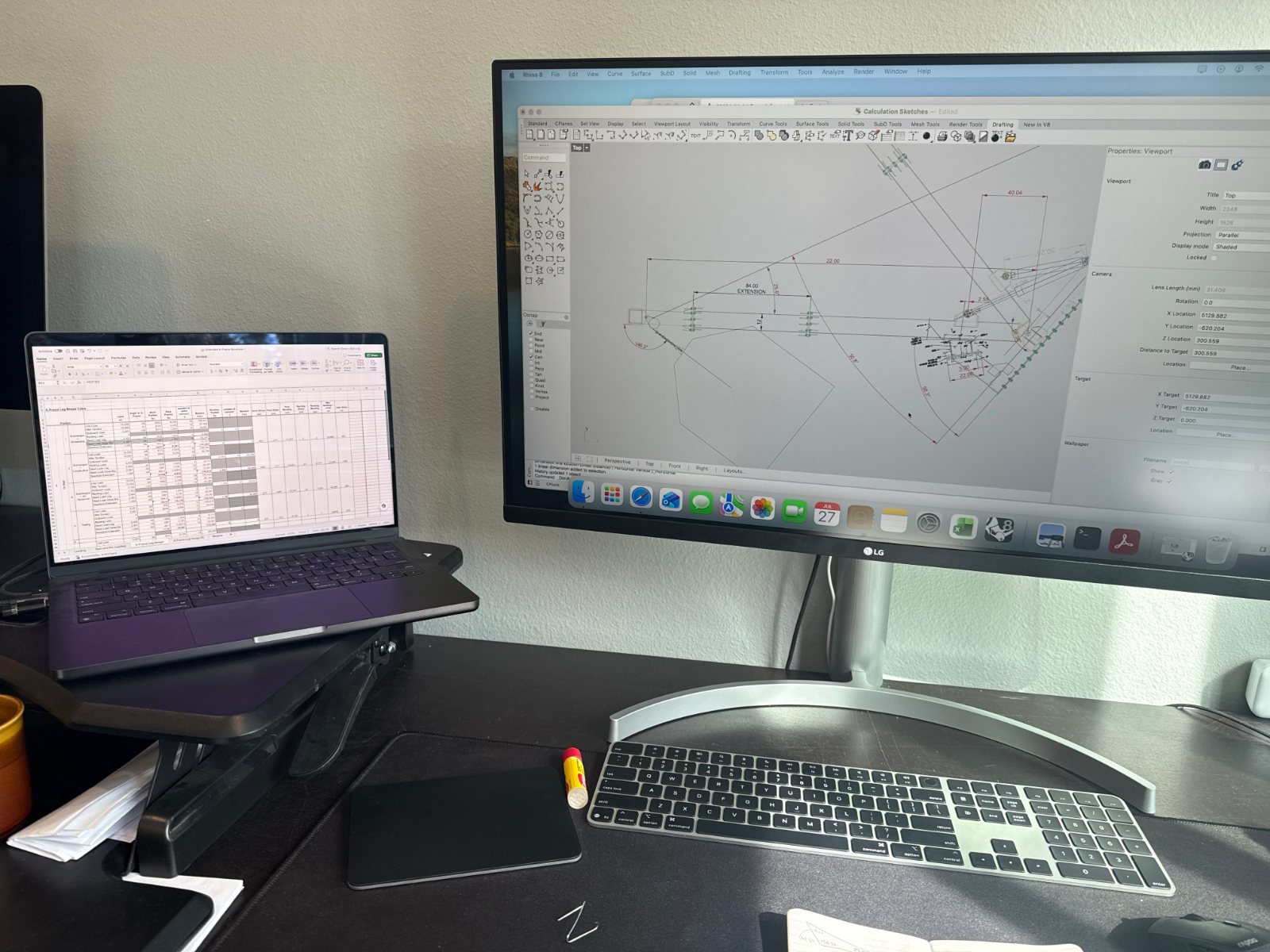 Desk with laptop and monitor showing a drawing in Rhino