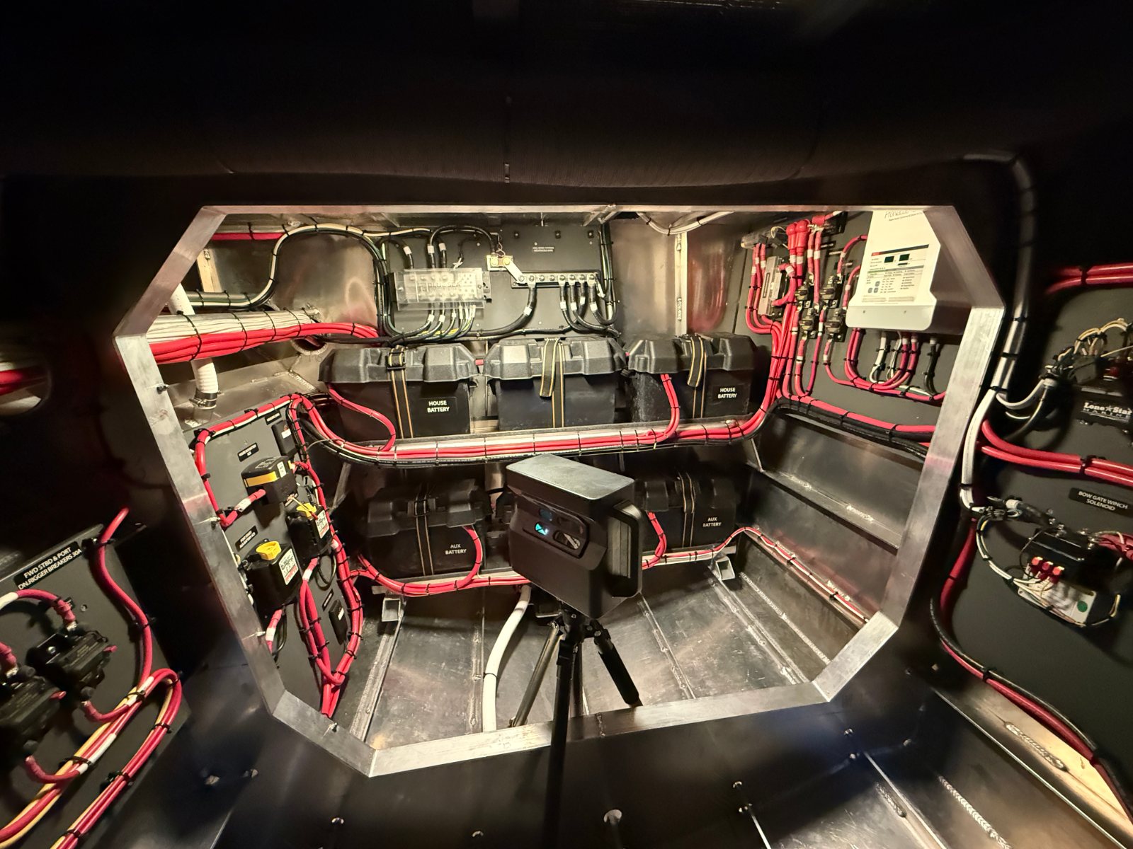 Electrical compartment with red and black wiring runs, a Matterport camera on its tripod in the middle