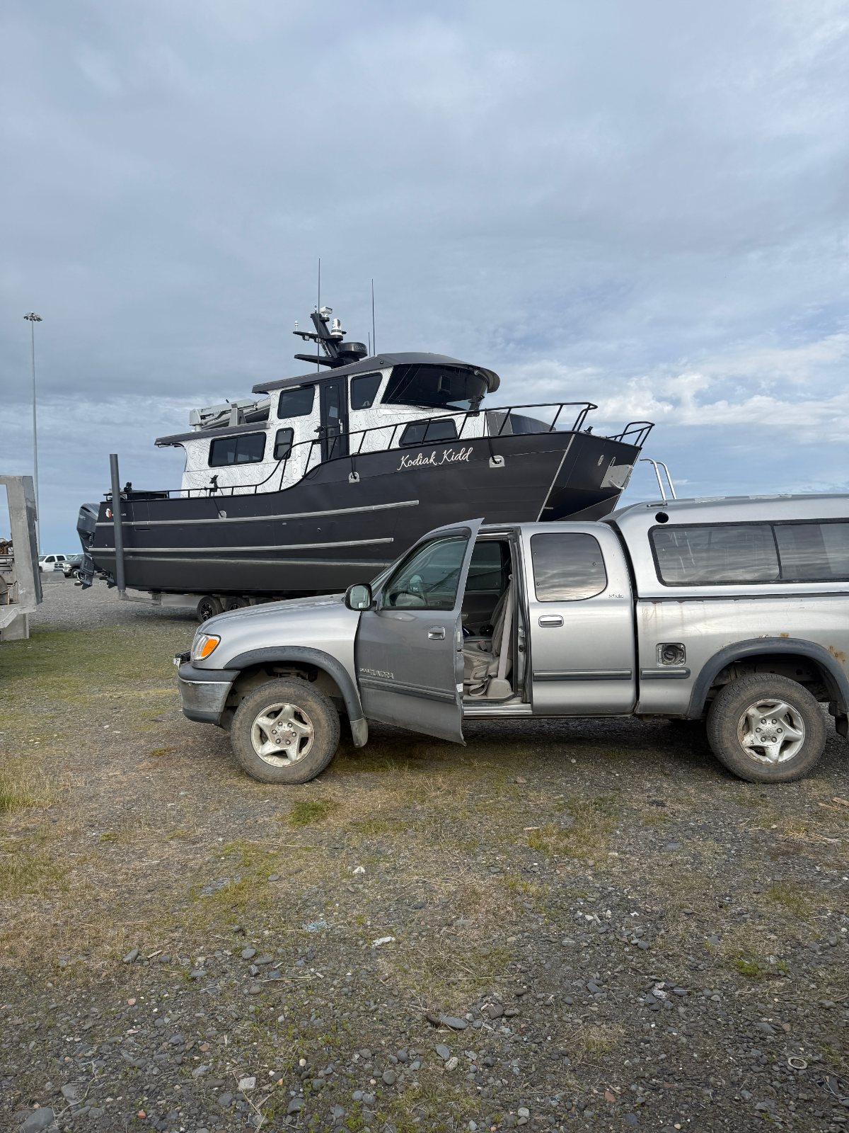 Aluminium boat on a trailer in the yard behind a pickup